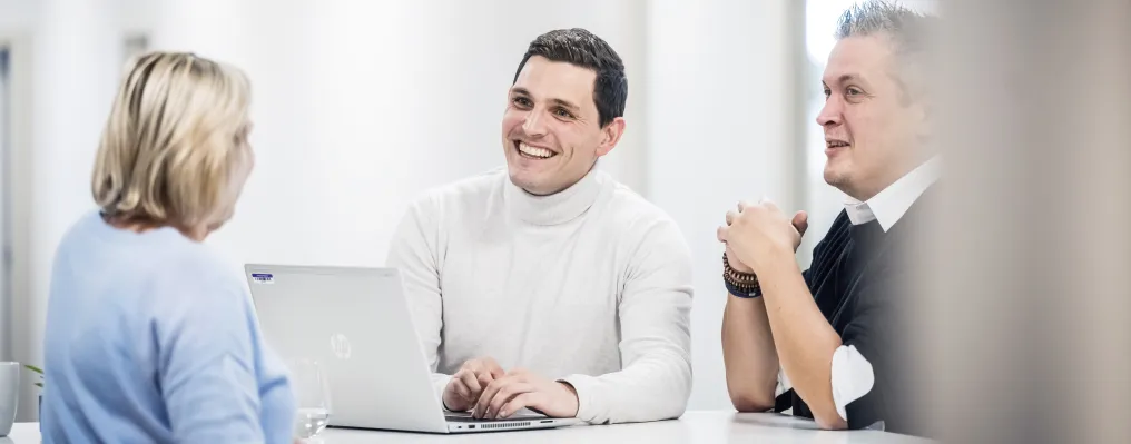 close up of three people at a table with laptop