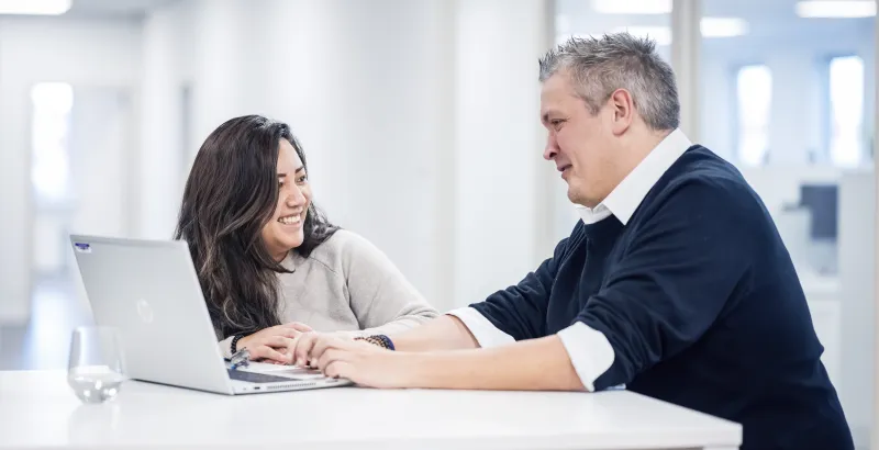 Close op of 2 people at a table with laptop